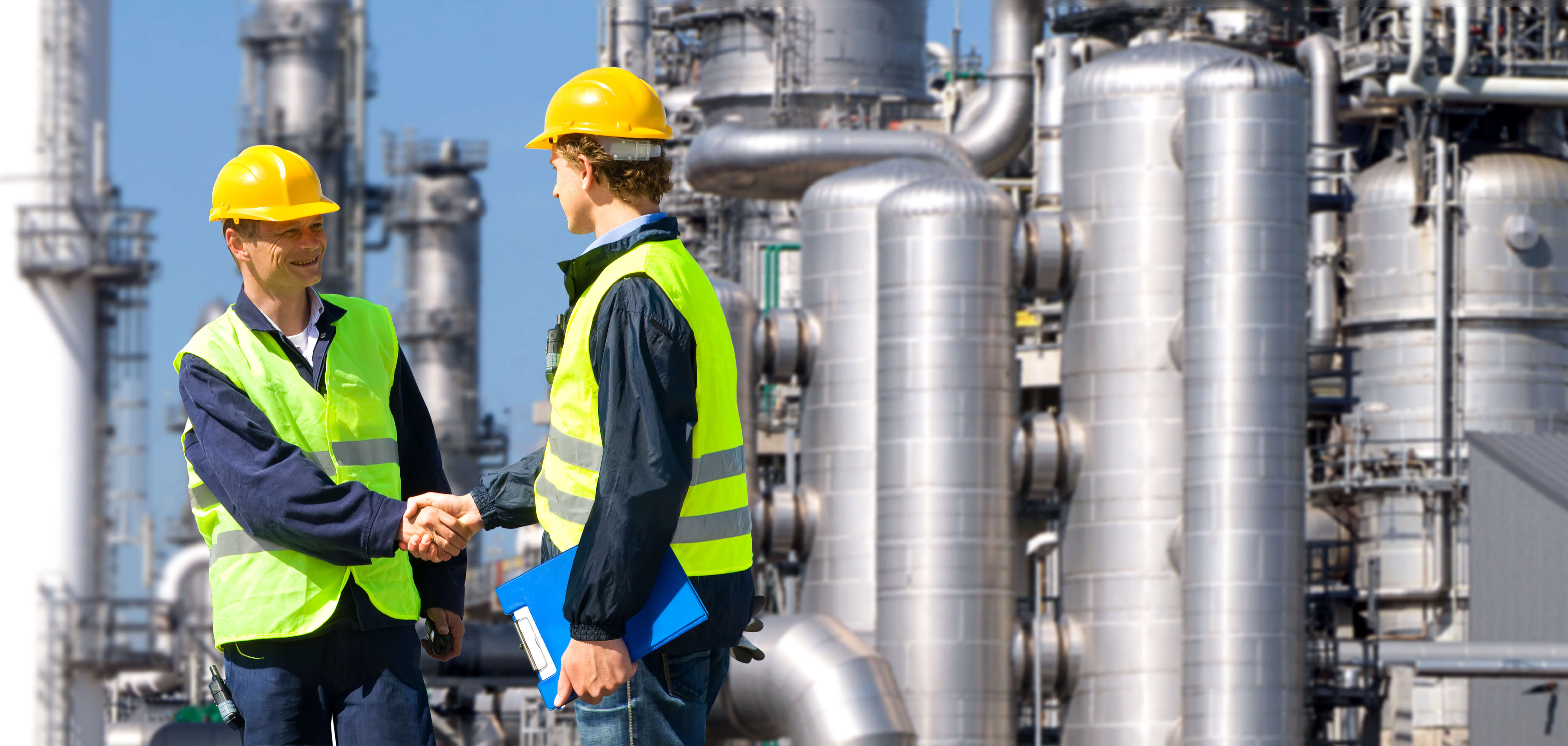 Workers shaking hands by tanks