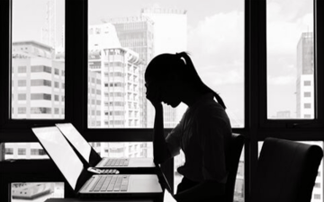 Woman at a laptop sits with her head in her hands 