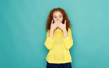 Woman standing with her hands over her mouth 