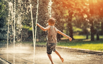 Boy plays in a sprinkler 