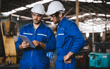 Two maintenance workers look over permits before a job 